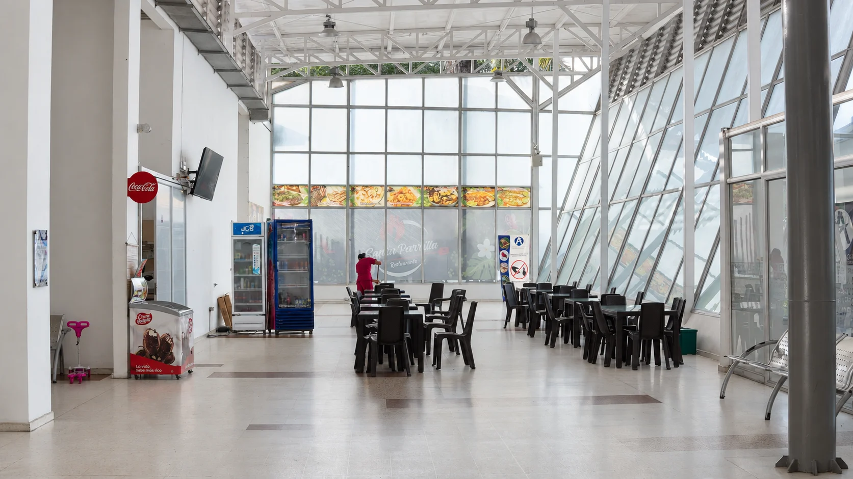 Interior de la terminal del aeropuerto, con mesas y amplios ventanales